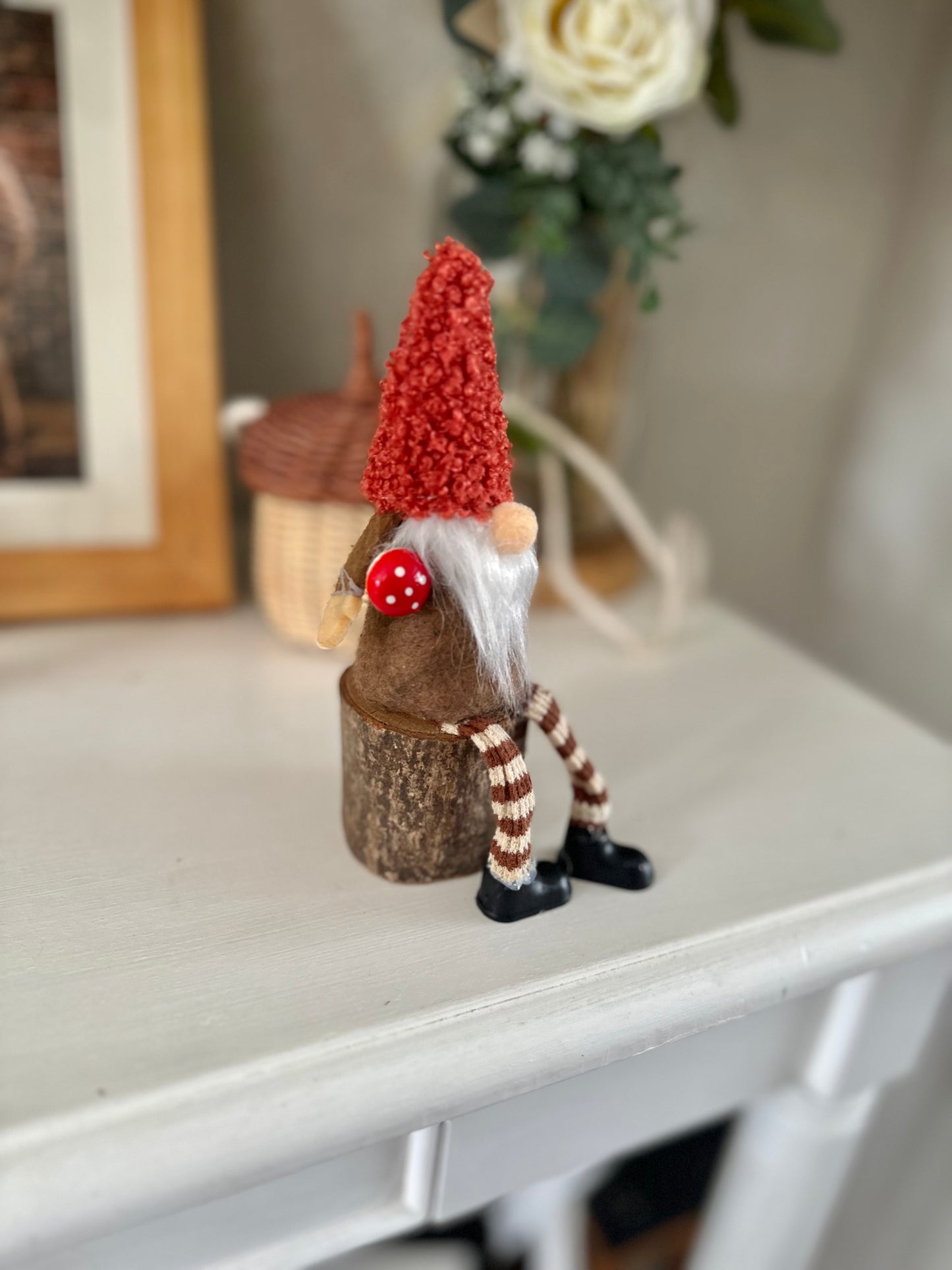 Sitting Gonk with rusty red hat on log