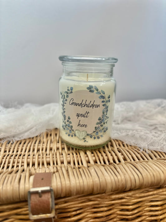 Glass jar candle with lid. Features a green and cream wreath with the words ‘grandchildren spoilt here’. Perfect gift for grandparents.