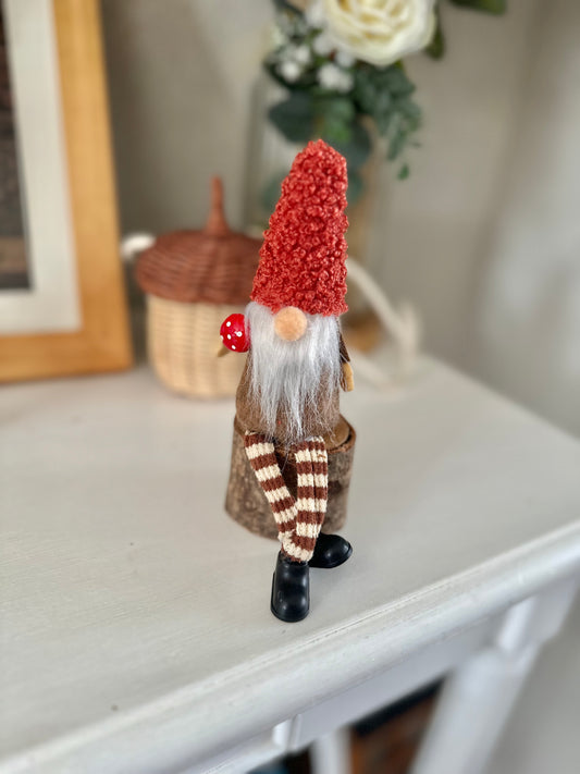 Sitting Gonk with rusty red hat on log