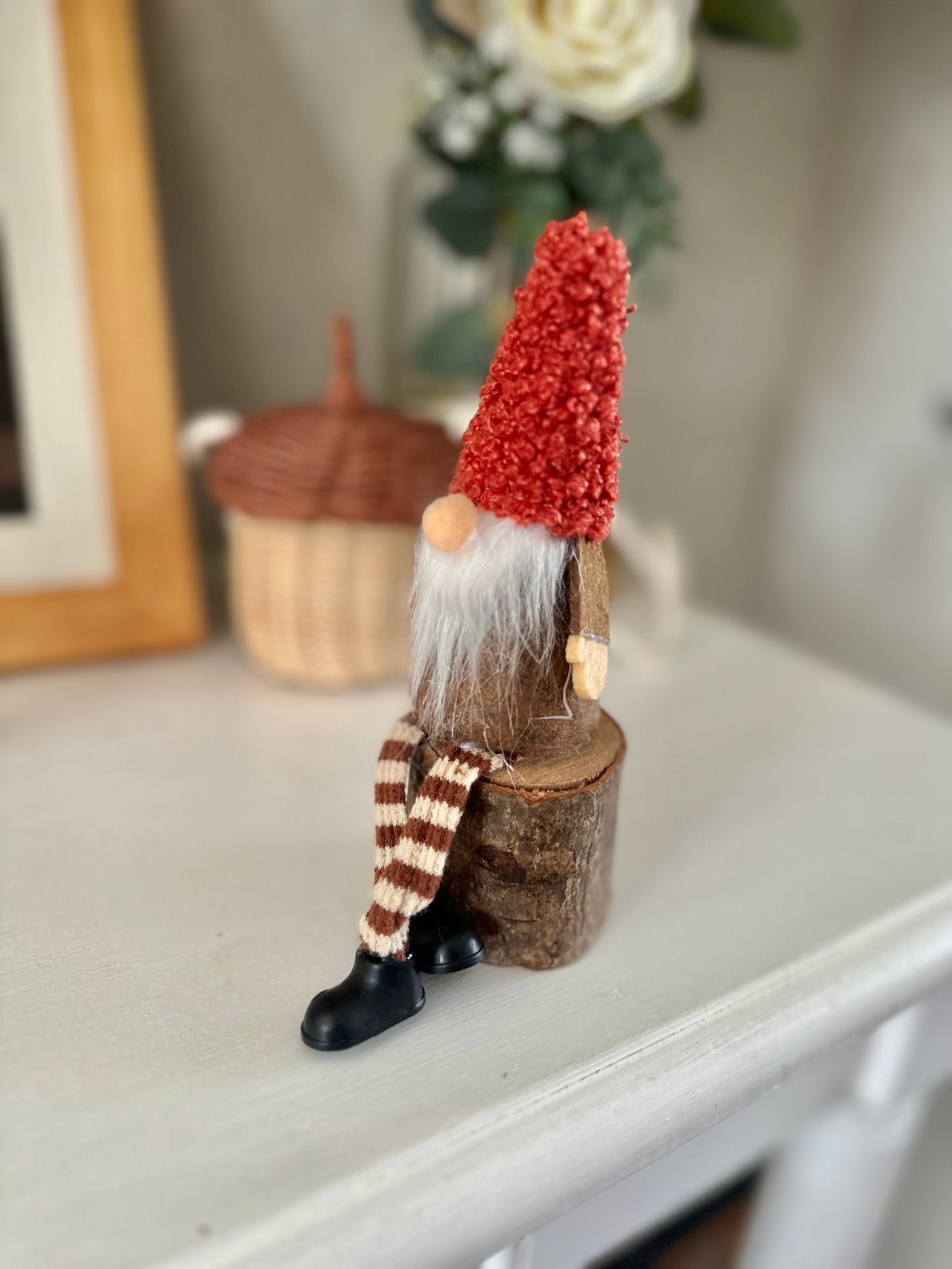 Sitting Gonk with rusty red hat on log